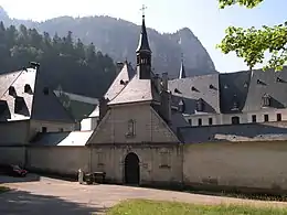 Porte d'entrée dans le mur d'enceinte donnant accès aux bâtiments aux toits gris d'un monastère.