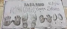 Empreintes au sol sur une dalle de béton. On y retrouve les mains et chaussures d'Emma Stone et Ryan Gosling à côté de leur nom, et le nom du film La La Land est écrit au sommet de la dalle. La date de prise des empreintes est inscrite en haut à droite : 7 décembre 2016.