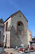 Le haut mur du chevet en pierre calcaire soutenu par deux contreforts d'angle. La vaste baie de style roman a été récemment murée. La nef est surmontée d'une salle percée d'une meurtrière.