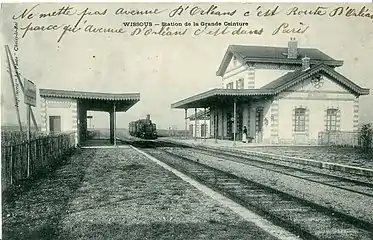 Ancienne carte postale montrant les voies, les quais et le bâtiment voyageurs de la gare de Wissous.