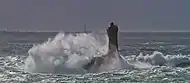 Des lames se brisant et écumant sur un phare pendant un coup de vent.