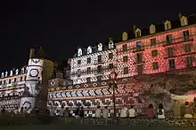 Vue nocturne d'une muraille et d'édifices illuminés de motifs géométriques
