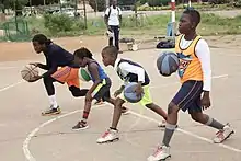 Élèves apprenant à manier un ballon de basket-ball au Bénin.