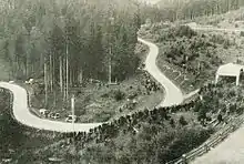 Photo d'une route de montagne serpentant avec des virages en épingle entre les arbres.