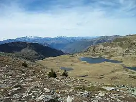 Les petits lacs à gauche sont nommés Estanys de Baciver, à droite ce sont les Estanys de Dalt de Baciver. Vue depuis le Col de Collada dels Estanys dels Rosaris à 2 507 m, en arrière plan on peut voir le Massif de la Maladeta avec ses glaciers.