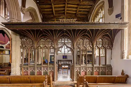 Dans une église une sorte de colonnade formant cloison très ajourée et richement ouvragée laisse apparaître une petite pièce avec table et bancs.