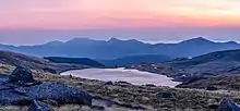 Dans la lumière douce d'un lever de soleil, une modeste étendue d'eau se réveille au milieu des montagnes.