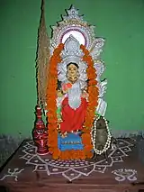 Alpana on an altar underneath a statue of the goddess Lakshmi