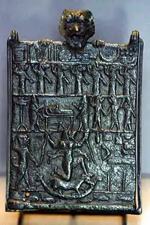 Photographie couleur d'une plaque de métal avec trois rangées de personnages en reliefs.