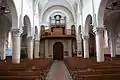 Vue de l'intérieur de l'église : les bas-côtés, le porche, l'orgue, la chapelle de la Miséricorde et les fonts baptismaux.