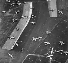 Photo aérienne noir et blanc de champs jonchés de carcasses d'aéronefs.