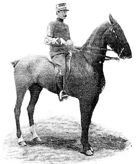 Photo en noir et blanc d'un cavalier en uniforme sur son cheval monté en bride présentant son profil droit.