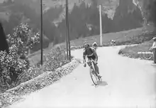 Photographie en noir et blanc d'un coureur cycliste dans la descente d'un col.