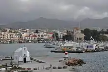 photographie en couleurs : un port : une petite église au premier plan ; une ville en arrière plan