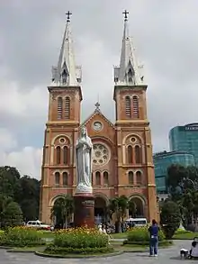 Façade d'une cathédrale, devant laquelle se tient une statue de la Vierge Marie.