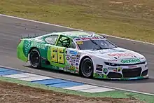 Photographie d'une voiture de NASCAR blanche sur l'avant, vert pomme à l'arrière, vue de trois-quarts droit, sur une piste sèche.