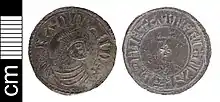 Photo des deux faces d'une pièce de monnaie, avec un portrait de profil grossier à l'avers et une petite croix au revers, les deux entourés de texte