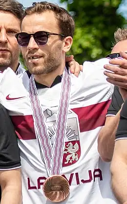 Photographie couleur d'un homme avec une médaille de bronze autour du cou