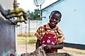 Garçonnet lavant son uniforme scolaire au robinet (Zimbabwe).