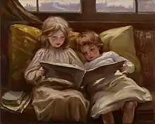 Two young children sit together reading a book