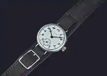 Photographie d'une montre à bracelet noir et cadran blanc