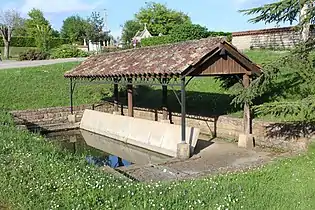 Un bassin rempli d'eau situé à proximité d'un petit abri en tuiles.