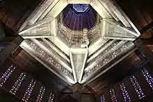 Vue en contre-plongée de la tour-lanterne de béton et des vitraux de l'église.