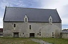 Photographie en couleurs de la façade d'un bâtiment munie de deux fenêtres à meneaux et de deux entrées.