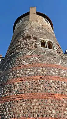 Vue d'une tour à partir de sa base, comportant une base décorée et des fenêtres dans ses parties supérieures