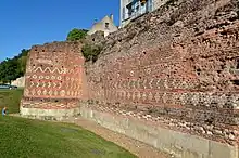 Photographie en couleurs d'un mur antique où les pierres dessinent des motifs géométriques.