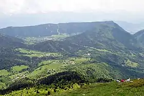 Vue plongeante sur des villages épars dans un paysage de montagne moyenne largement occupé par la forêt.