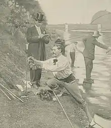 gravure noir et blanc : des pêcheurs au bord d'une rivière surveillés par un homme en costume et haut de forme