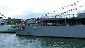 Avant-gauche d'un navire-école de guerre arborant le pavillon de la marine à sa proue.