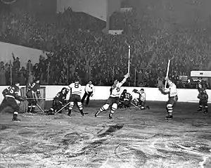 Photo noir et blanc d'un match où deux des joueurs lèvent les bras après un but marqué.