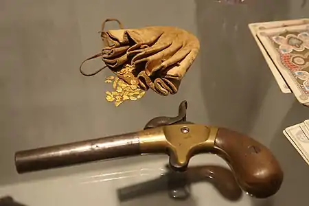 Bourse en cuir et pépites d'or fluviales (XIXe siècle). Petit pistolet de jeu à un coup (vers 1850), acier, laiton, bois. Cartes à jouer.
