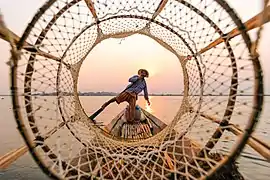 Le filet du pêcheur dessine au premier plan une série de cercles concentriques, à travers lesquels on aperçoit un lac tranquille et la longueur d'un petit bateau, et au centre un pêcheur, avec le soleil dans le prolongement de sa tête. Il pousse de sa jambe sur un pieu sortant de l'eau.