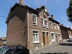 Des habitations groupées par trois construites en parpaings.