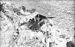 Photographie en noir et blanc d'une équipe d'hommes sous un bivouac.