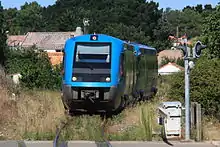 Deux autorails X 73500 arrivant en gare, cette photo permet de voir que la voie est envahie par les herbes.