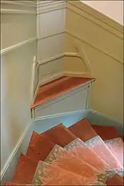 Photo en couleur et en plongée de quelques marches en bois avec tapis d'escalier aux motifs évoquant des flammes