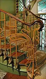 Photo en couleur d'un départ d'escalier avec rampe ouvragée en arabesques