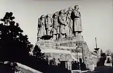 Un monument de grande hauteur représentant Staline à la tête d'une file d'individu.