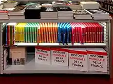 Meuble bas avec étagères dans le rayon histoire d'une librairie. Sur l'étagère du bas sont stockés des exemplaires de lHistoire mondiale de la France.