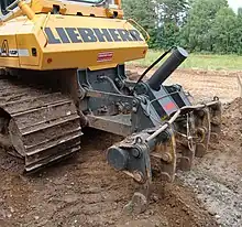 Ripper sur chenillard. Il est surtout utilisé en défrichage et avant plantation forestière, d'arbres fruitiers ou de haies.