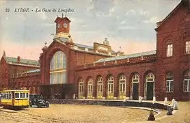 Automobile et tram devant la gare.