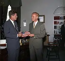Un homme offre un drapeau américain à un autre.
