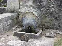 Photographie en couleurs d'une fontaine en pierre en forme de tonneau.