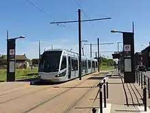 Vue des quais et du mobilier urbain de la station de tramway Taffin, avec une rame à quai.