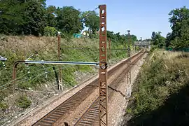 Vue d'une ligne ferroviaire électrifiée à double voie construite en tranchée.