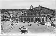 Entrée de la place des Buisses (à gauche de la photo) vers 1910 vue de la place de la gare. Les maisons à gauche de la photo sont détruites vers 1965